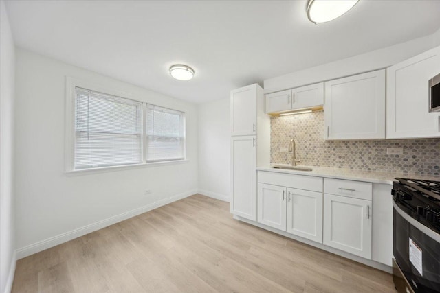 6357 W Addison St Unit Gse, Chicago, IL 60634 - kitchen featuring a sink, black range with gas stovetop, light countertops, tasteful backsplash, and light wood-style flooring
