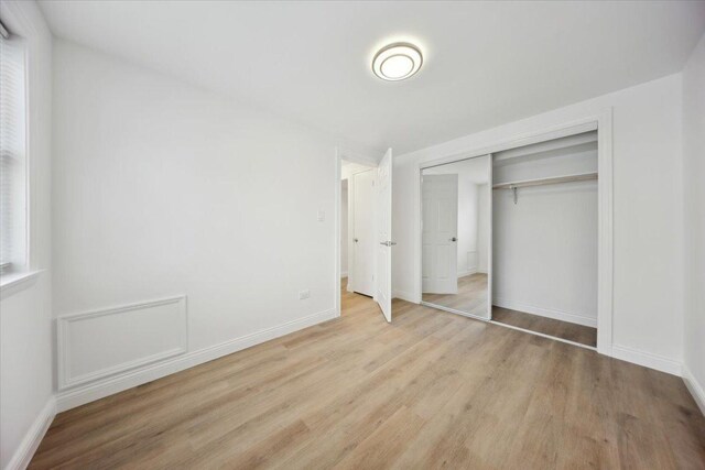 6357 W Addison St Unit Gse, Chicago, IL 60634 - unfurnished bedroom with wood finished floors, a closet, and baseboards