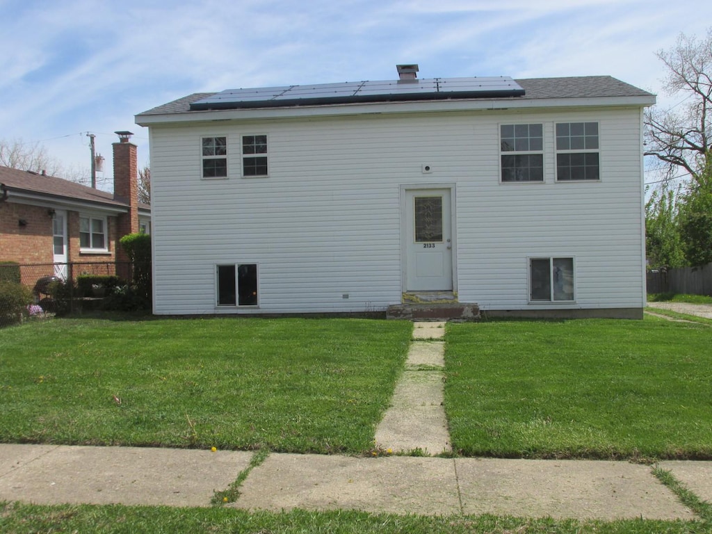 2133 Sherman Ave, North Chicago, IL 60064 - rear view of house featuring solar panels and a lawn