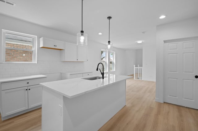 8317 S Constance Ave, Chicago, IL 60617 - kitchen featuring a sink, white cabinetry, backsplash, light wood-type flooring, and decorative light fixtures