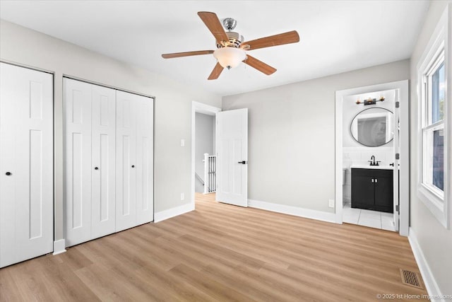 266 Merrill Ave, Calumet City, IL 60409 - unfurnished bedroom featuring a sink, light wood-style flooring, multiple closets, and baseboards
