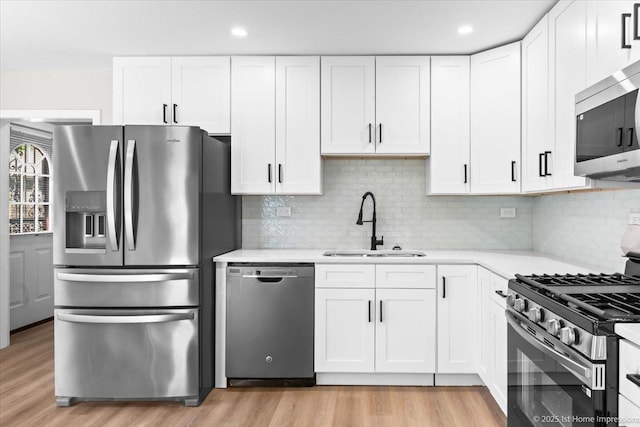 266 Merrill Ave, Calumet City, IL 60409 - kitchen with appliances with stainless steel finishes, a sink, light wood-style flooring, light countertops, and white cabinetry