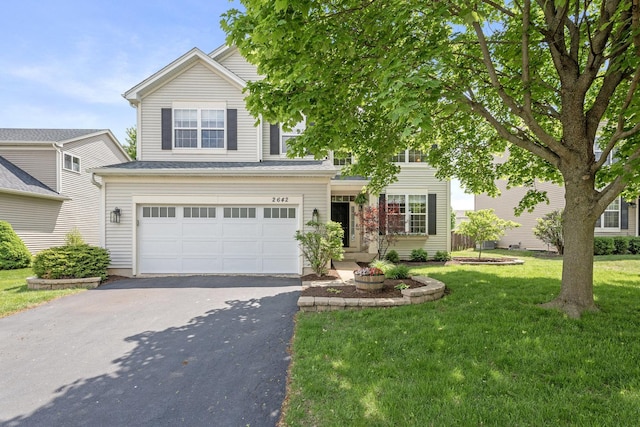 view of front of house with asphalt driveway, a front yard, and an attached garage