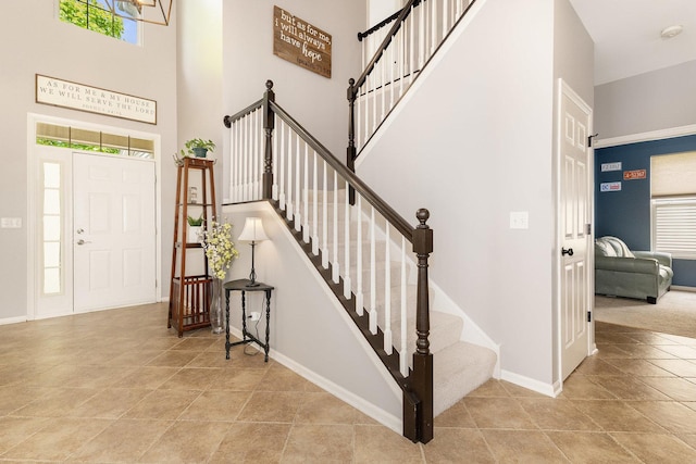 entryway featuring a towering ceiling, baseboards, stairs, and tile patterned flooring