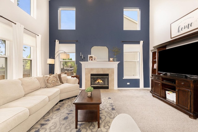 living area featuring a towering ceiling, a tiled fireplace, and carpet flooring