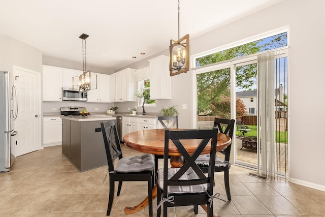 dining room with a chandelier, light tile patterned flooring, and baseboards