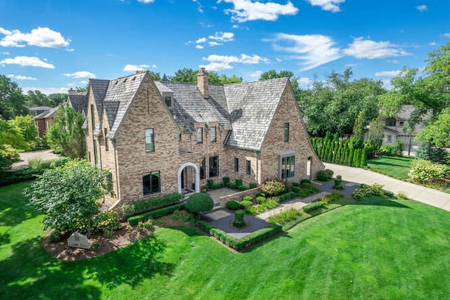 31 Concord Dr, Oak Brook, IL 60523 - tudor-style house featuring a chimney, a front yard, stone siding, and a high end roof