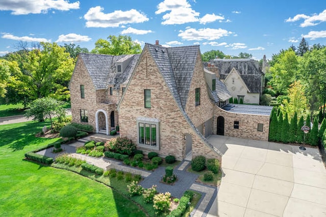 31 Concord Dr, Oak Brook, IL 60523 - tudor home featuring stone siding, driveway, a front lawn, an attached garage, and a high end roof
