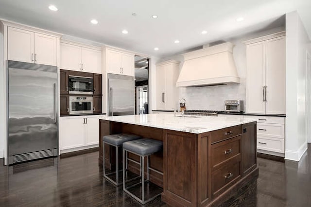 31 Concord Dr, Oak Brook, IL 60523 - kitchen with built in appliances, custom range hood, recessed lighting, a breakfast bar, and a center island with sink
