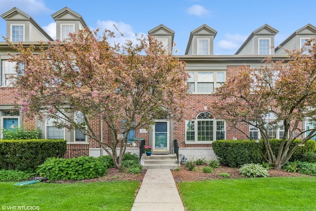 townhome / multi-family property with brick siding and a front yard