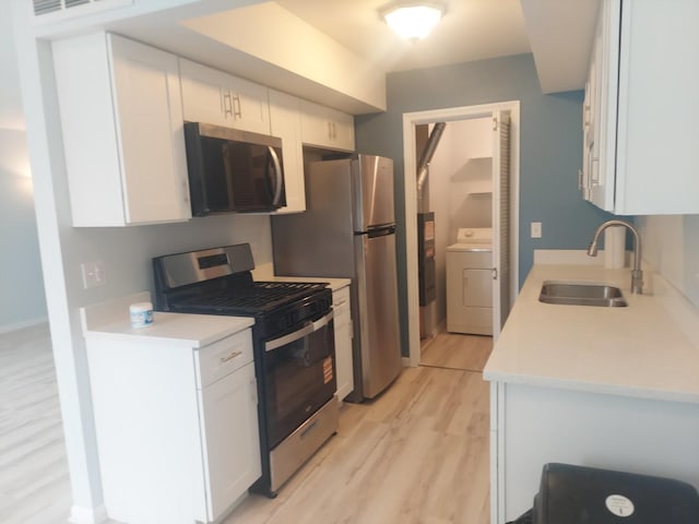 kitchen with stainless steel appliances, washer / clothes dryer, a sink, light wood finished floors, and white cabinets