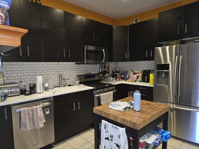 948 N California Ave, Chicago, IL 60622 - kitchen with stainless steel appliances, dark cabinetry, light tile patterned flooring, and a sink