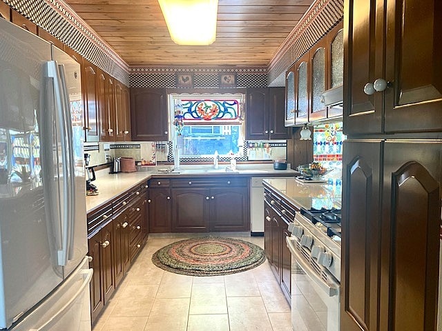 kitchen featuring freestanding refrigerator, gas range, light countertops, wooden ceiling, and light tile patterned floors