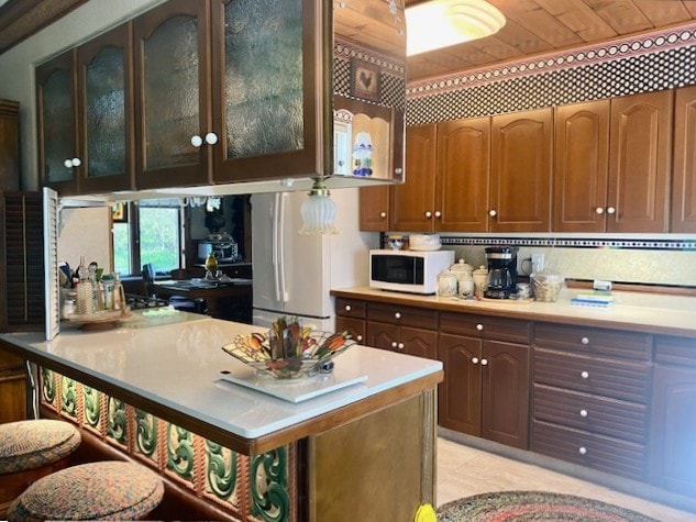 kitchen with white appliances, light countertops, and glass insert cabinets