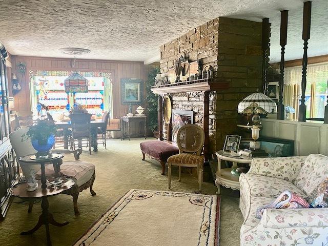 carpeted living area with a textured ceiling and a stone fireplace