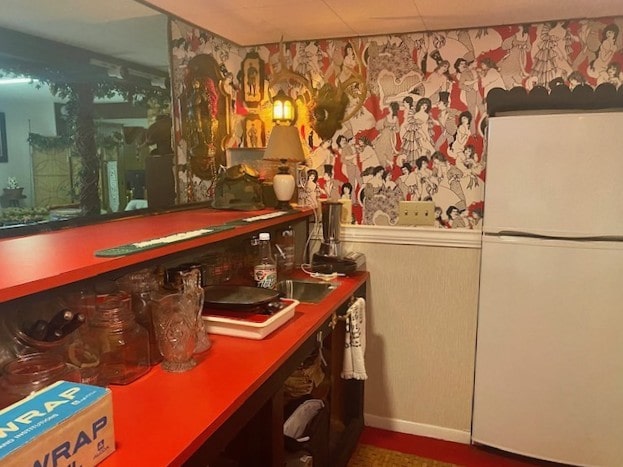 bar with freestanding refrigerator and baseboards