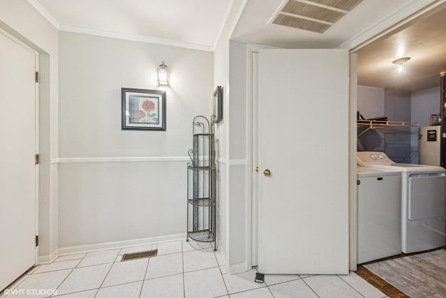 laundry area featuring separate washer and dryer, light tile patterned floors, crown molding, and baseboards