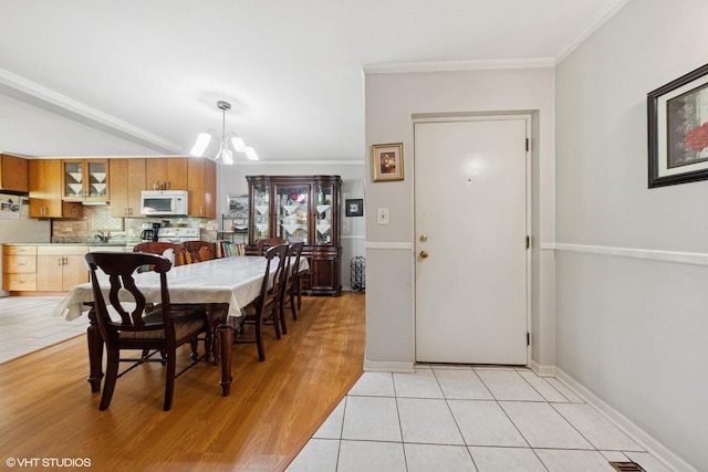 dining room featuring a chandelier, ornamental molding, baseboards, and light wood-type flooring