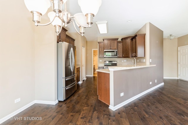 kitchen featuring stainless steel appliances, dark wood-type flooring, baseboards, a chandelier, and a peninsula