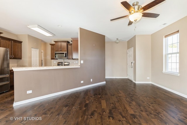 kitchen with appliances with stainless steel finishes, dark wood finished floors, light countertops, and ceiling fan