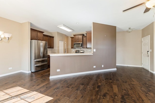 kitchen with appliances with stainless steel finishes, dark wood finished floors, a ceiling fan, and baseboards