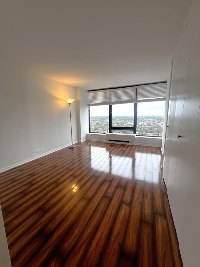 spare room featuring dark wood-style flooring and baseboards