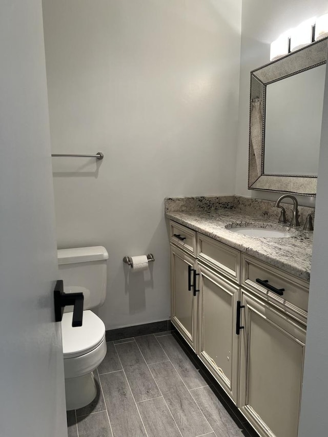 bathroom featuring toilet, baseboards, and vanity