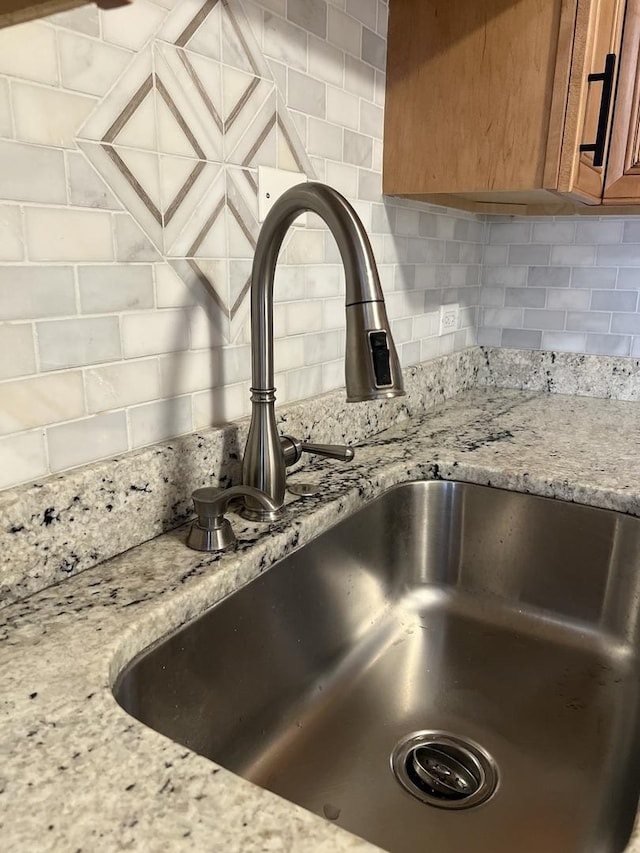 kitchen view of a sink, brown cabinets, and backsplash