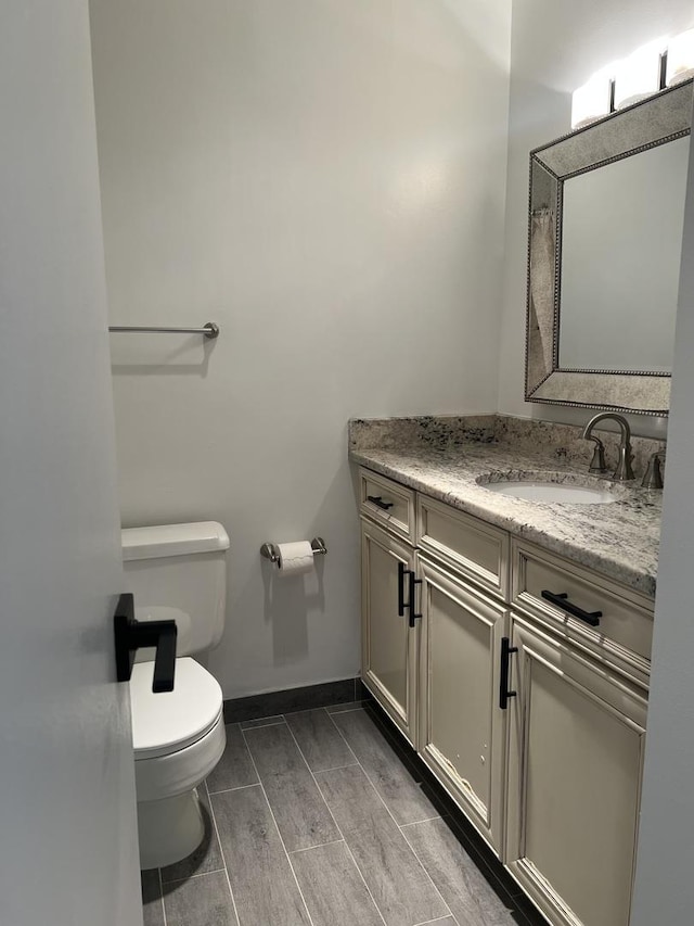 full bath with toilet, baseboards, and vanity