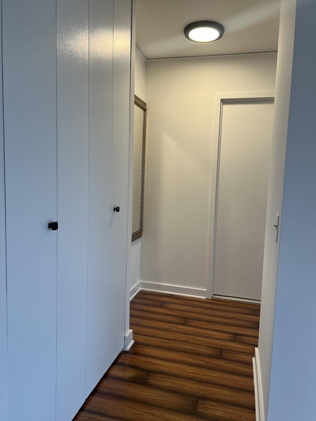 corridor with dark wood-style floors and baseboards