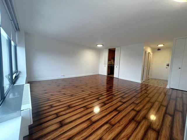 unfurnished living room featuring dark wood finished floors and baseboards