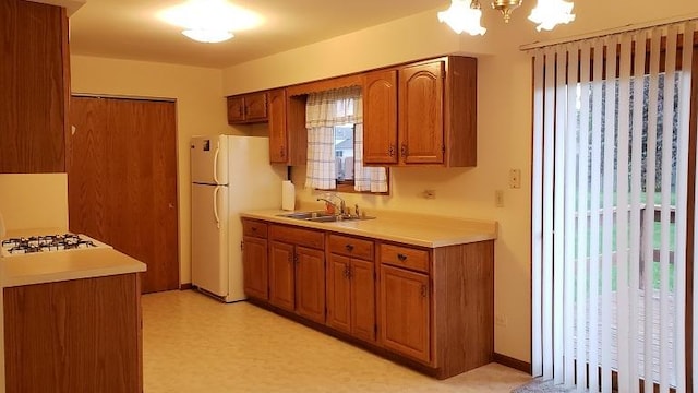 kitchen featuring freestanding refrigerator, brown cabinets, a sink, and healthy amount of natural light