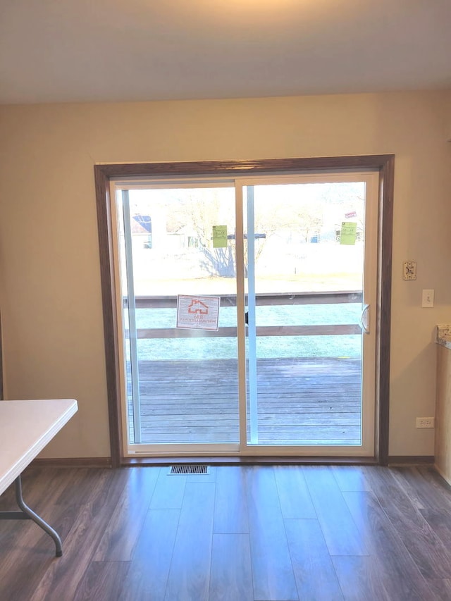 doorway with wood finished floors and baseboards