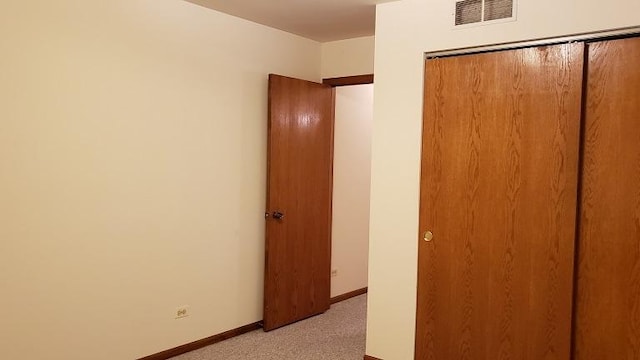 unfurnished bedroom featuring light carpet, baseboards, and a closet