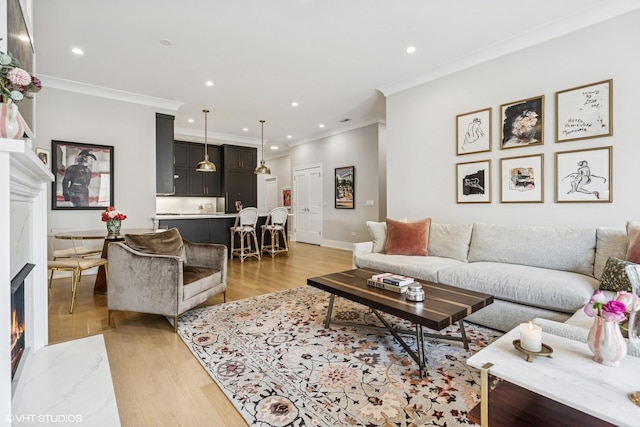 living area with a fireplace with flush hearth, crown molding, light wood-style floors, recessed lighting, and baseboards