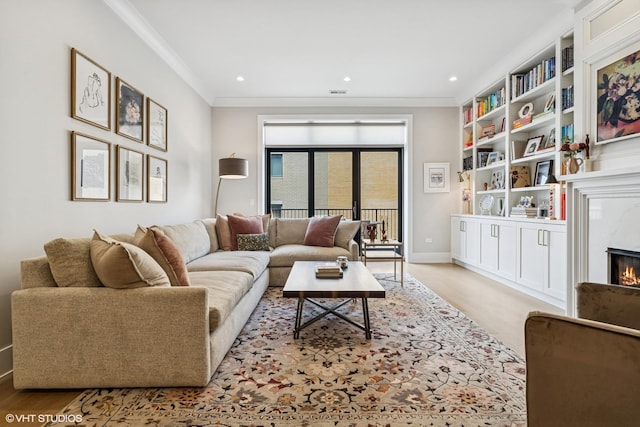 living area with ornamental molding, a high end fireplace, baseboards, and recessed lighting