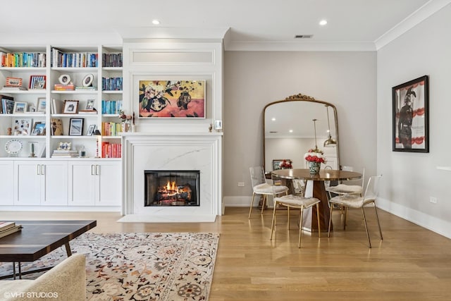 living room with light wood-style flooring, crown molding, a fireplace, recessed lighting, and baseboards