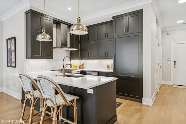 kitchen with wall chimney exhaust hood, light wood-style floors, backsplash, light countertops, and baseboards