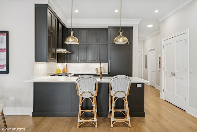 kitchen with light countertops, decorative backsplash, light wood-style floors, crown molding, and recessed lighting