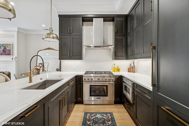 kitchen featuring high quality appliances, wall chimney range hood, a sink, light wood-style floors, and tasteful backsplash
