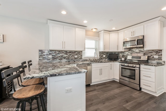 1080 E Prairie Ave, Des Plaines, IL 60016 - kitchen featuring appliances with stainless steel finishes, a peninsula, a kitchen bar, white cabinets, and recessed lighting