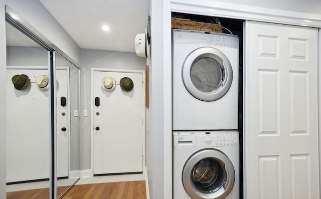 laundry area with stacked washer and clothes dryer, light wood-style floors, and recessed lighting