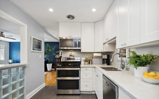 kitchen featuring appliances with stainless steel finishes, a sink, white cabinets, and recessed lighting