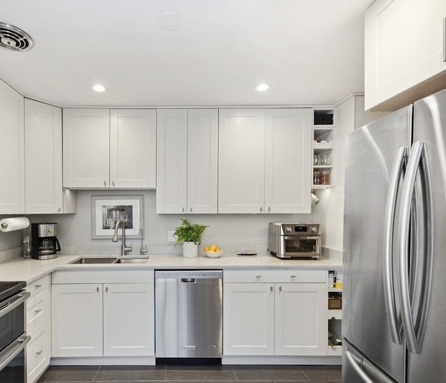 kitchen with stainless steel appliances, a sink, white cabinets, light countertops, and recessed lighting