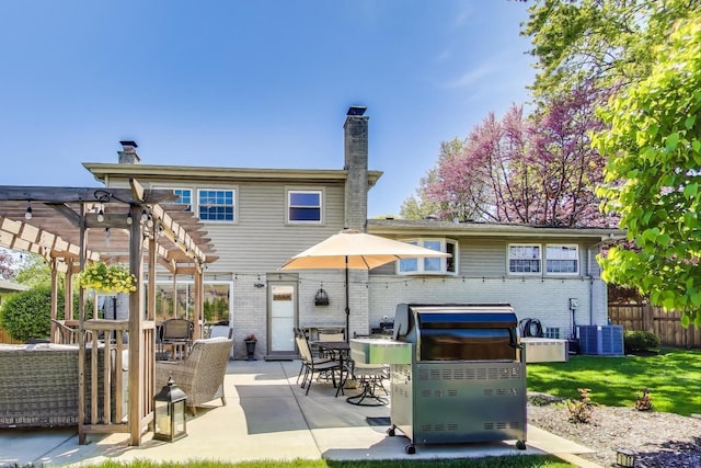 back of property with a pergola, a chimney, brick siding, fence, and a patio