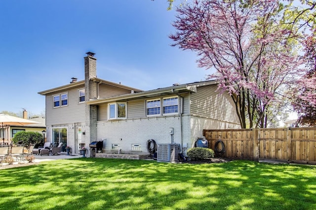 back of property featuring a chimney, brick siding, a patio area, central AC unit, and a gate