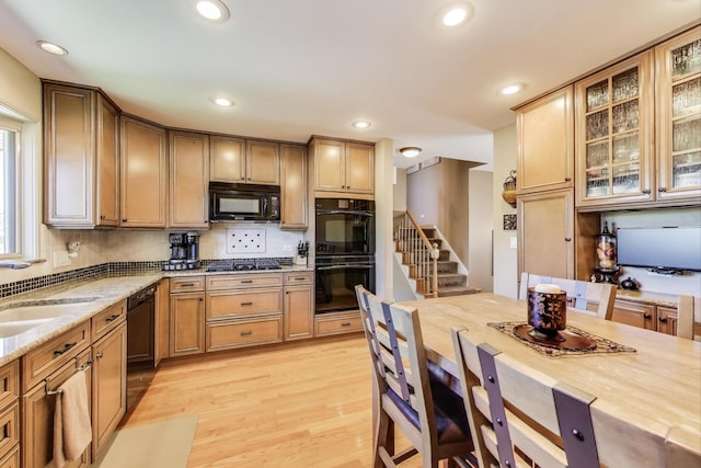 kitchen featuring black appliances, light wood finished floors, light stone counters, tasteful backsplash, and recessed lighting