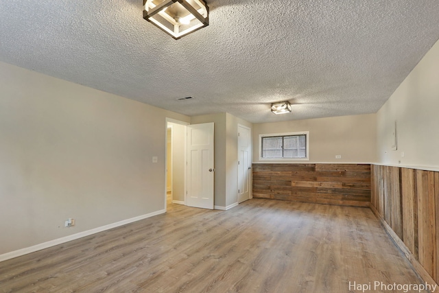25269 W Anderson St, Ingleside, IL 60041 - empty room featuring wood finished floors, a textured ceiling, wood walls, and a wainscoted wall