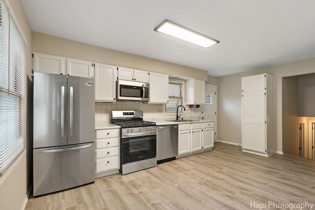 25269 W Anderson St, Ingleside, IL 60041 - kitchen with stainless steel appliances, a sink, white cabinets, backsplash, and light wood-style floors