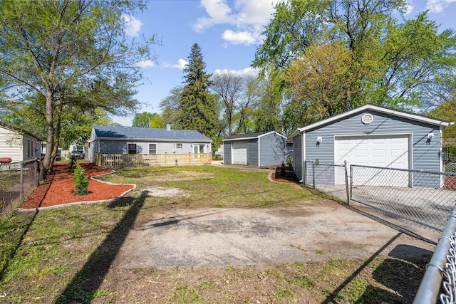 view of yard featuring a detached garage, an outbuilding, driveway, and fence